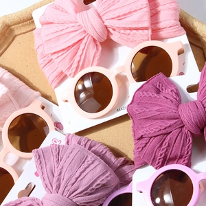 Close-up of baby knit headbands with large bows and retro round sunglasses in soft pastel tones