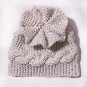 Détail d'un bonnet tricoté pour bébé avec une grande fleur faite main et bord côtelé