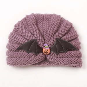 Detailed view of purple knit baby hat with Halloween pumpkin and bat wing decorations