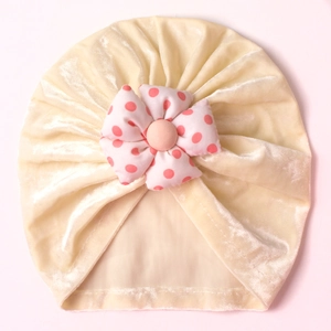 Detail of baby velvet turban hat featuring a handcrafted pink polka dot flower detail
