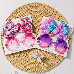 Close-up of floral bow headbands and sunglasses on a woven mat in bright summer style