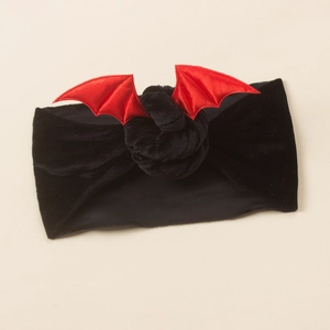 Detailed close-up of a soft black velvet baby headband with red satin bat wings decoration