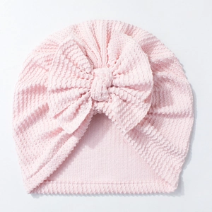 Detailed view of pink waffle knit baby turban hat with a large decorative soft bow