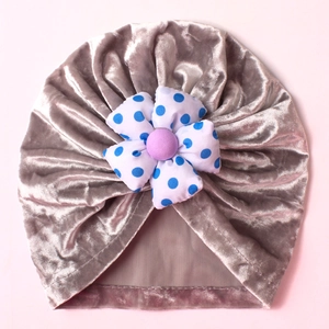 Detail of silver velvet baby beanie featuring a blue polka dot fabric flower ornament