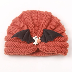 Detail of baby knitted hat with ghost, pumpkin resin charm and black bat wings decoration