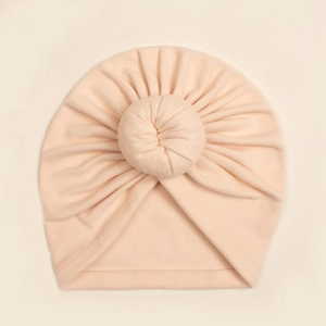 Detail eines weichen pfirsichfarbenen Baby-Turbans mit Faltenknoten und glatten Nähten
