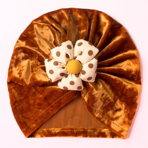 Detailed view of bronze velvet baby turban with a polka dot floral accent and button