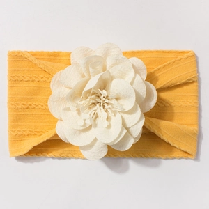 Détail d'un bandeau jaune pour bébé avec une grande fleur en tissu blanc multicouche