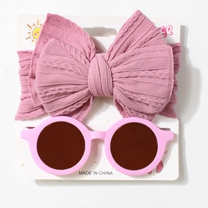 Detailed view of pink knitted bow headband and round sunglasses on a display card