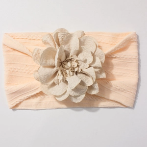 Détail macro du bandeau élastique tricoté pour bébé avec une grande fleur en tissu abricot
