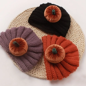 Detail shot of three knitted baby pumpkin hats in black, purple, and orange for Halloween
