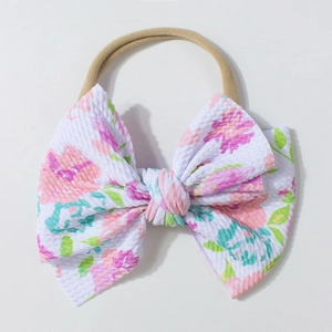 Dettaglio fascia neonata con fiocco floreale goffrato e trama elastica in nylon morbido