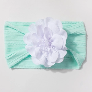Gros plan d'un bandeau bébé vert menthe avec une grande fleur blanche en relief 3D