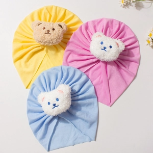Three soft cotton baby turban hats in pink yellow and blue with plush bear details