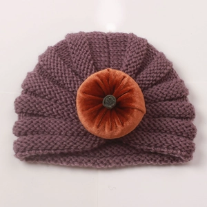 Detail of dark purple ribbed knit baby hat with orange velvet pumpkin decoration