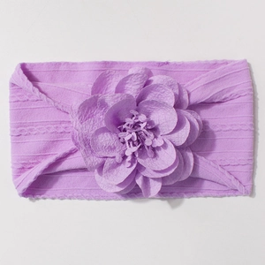 Détail d'un bandeau violet pour bébé en jacquard avec fleur en tissu et maille côtelée