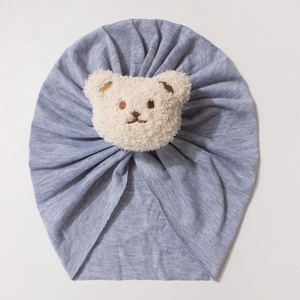 Detailed shot of baby knit turban hat in blue with a cute 3D plush bear ornament