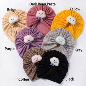 Flat lay of baby waffle knit turban hats in seven colors with plush smiling cloud detail