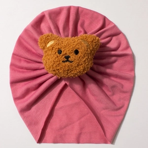 Close-up detail of soft elastic knit baby beanie featuring a brown plush bear patch