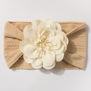 Vue détaillée du bandeau pour bébé en tricot beige avec une fleur en tissu 3D