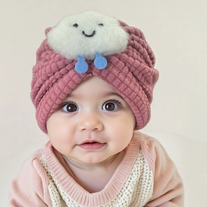 Detail of pink knit baby beanie with cute cloud motif and soft ripple texture