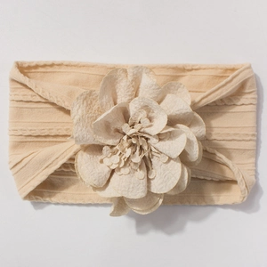 Détail du bandeau beige en maille avec texture côtelée et grande fleur en tissu doux