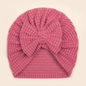 Détail du bonnet turban bébé en maille gaufrée rose avec un grand nœud de décoration
