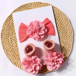 Detailed view of baby headband and socks set with large 3D floral accents in coral pink