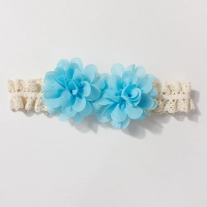 Close-up of sky blue and beige chiffon flowers on a delicate lace baby headband