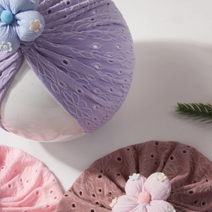 Close-up of baby turban hats with hollow eyelet texture and large floral accents