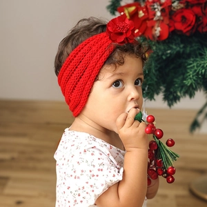Detail of red knitted baby headband featuring a 3D floral accent for holiday occasions
