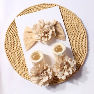 Detailed close-up of baby headband and socks set with elegant floral jacquard design