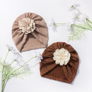Vue détaillée des bonnets de naissance en maille côtelée avec fleurs décoratives