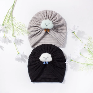 Close-up of baby knit hats in grey and black with cute white plush cloud patches