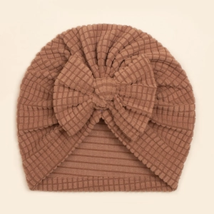 Détail de la texture gaufre et du grand nœud sur ce turban marron pour bébé
