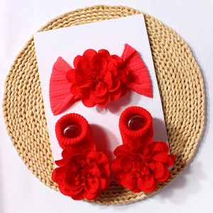 Flat lay of red floral baby headband and matching socks set on a rustic woven mat