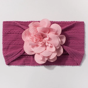 Détail d'un bandeau bébé en nylon violet rose avec une grande fleur en tissu rose clair