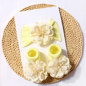 Detailed view of baby headband and socks set with 3D floral accents on woven mat