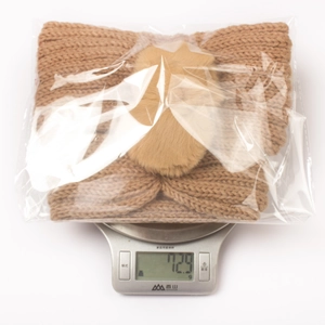 Detailed close-up of a warm brown knitted headband with a soft faux fur pom-pom detail