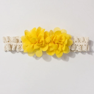 Detailed close-up of white lace baby headband with two layered yellow chiffon flowers