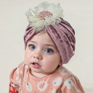 Detail of baby velvet turban hat in dusty rose with large lace floral decoration