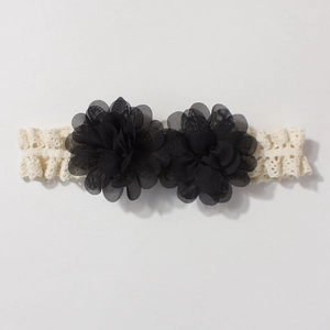 Close-up of baby lace headband with black mesh chiffon flowers on a white background