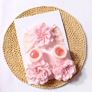 Close-up of pink baby headband and socks set with chiffon flowers on a woven mat