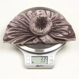 Detail shot showing a purple velvet baby turban weighing 33.4g on a digital scale