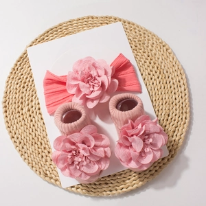Close-up of pink baby headband and socks set with large decorative fabric flowers