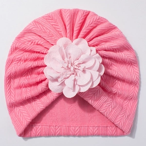 Détail de texture en tricot doux et fleur en tissu sur un bonnet pour bébé rose vif