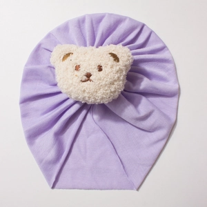 Detail of soft purple baby turban hat with a cute 3D cream plush bear patch decoration