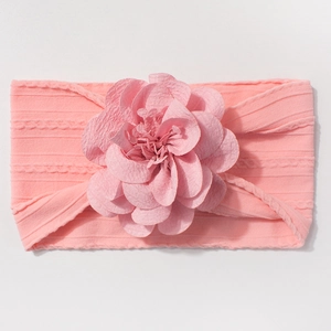 Gros plan sur un bandeau bébé rose en jacquard avec une grande fleur 3D et texture côtelée