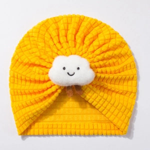 Detail of yellow waffle knit baby beanie featuring a plush smiling white cloud patch