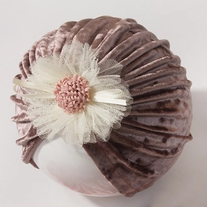 Detail view of pink velvet baby turban with a large white lace flower decoration